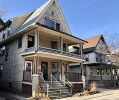 Two-story gray wood-frame house with a covered front porch on a residential street.
