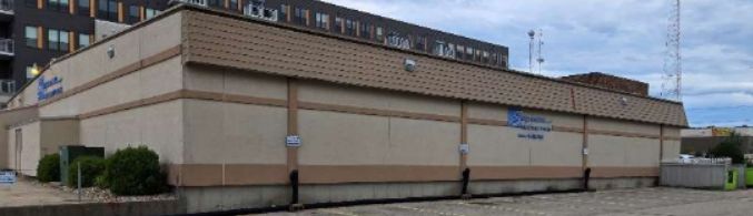 Exterior view of a low-rise tan commercial building slated for demolition in District 19.
